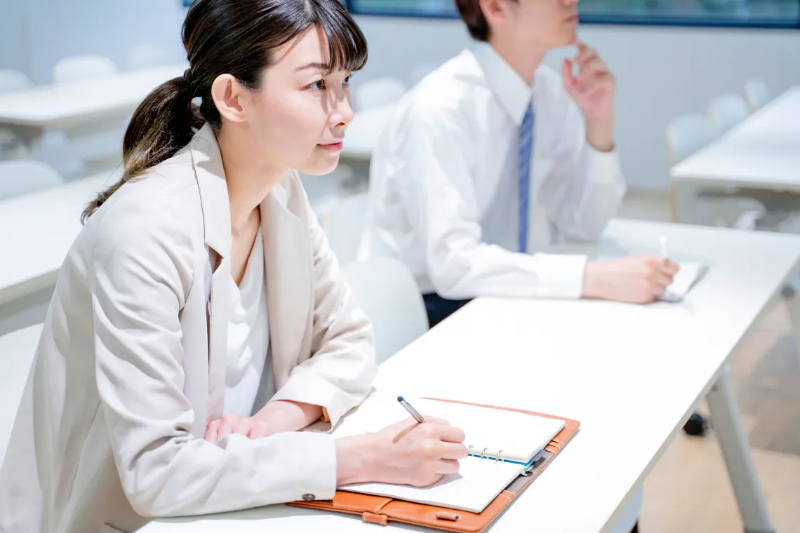 会議室で資料を見ながらセミナーを受ける若手ビジネスパーソン