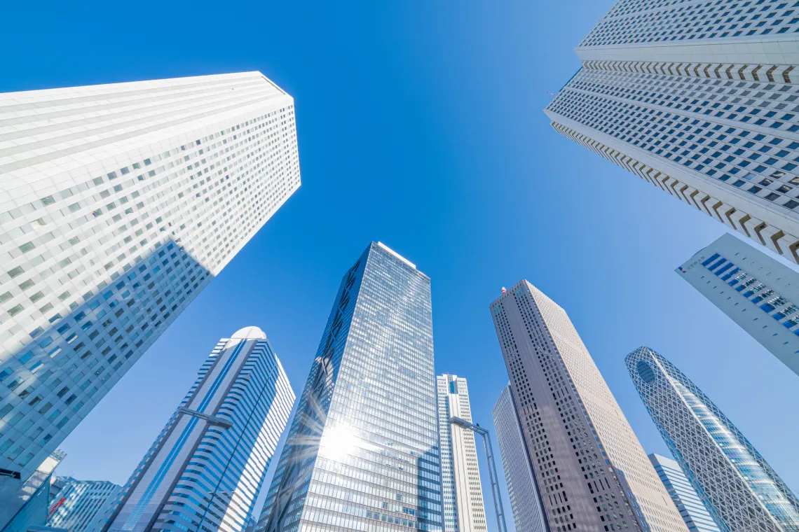青空の下にそびえる高層ビル群の風景